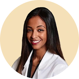 Dr. Hanan Naser, dentist wearing white coat, smiling at camera