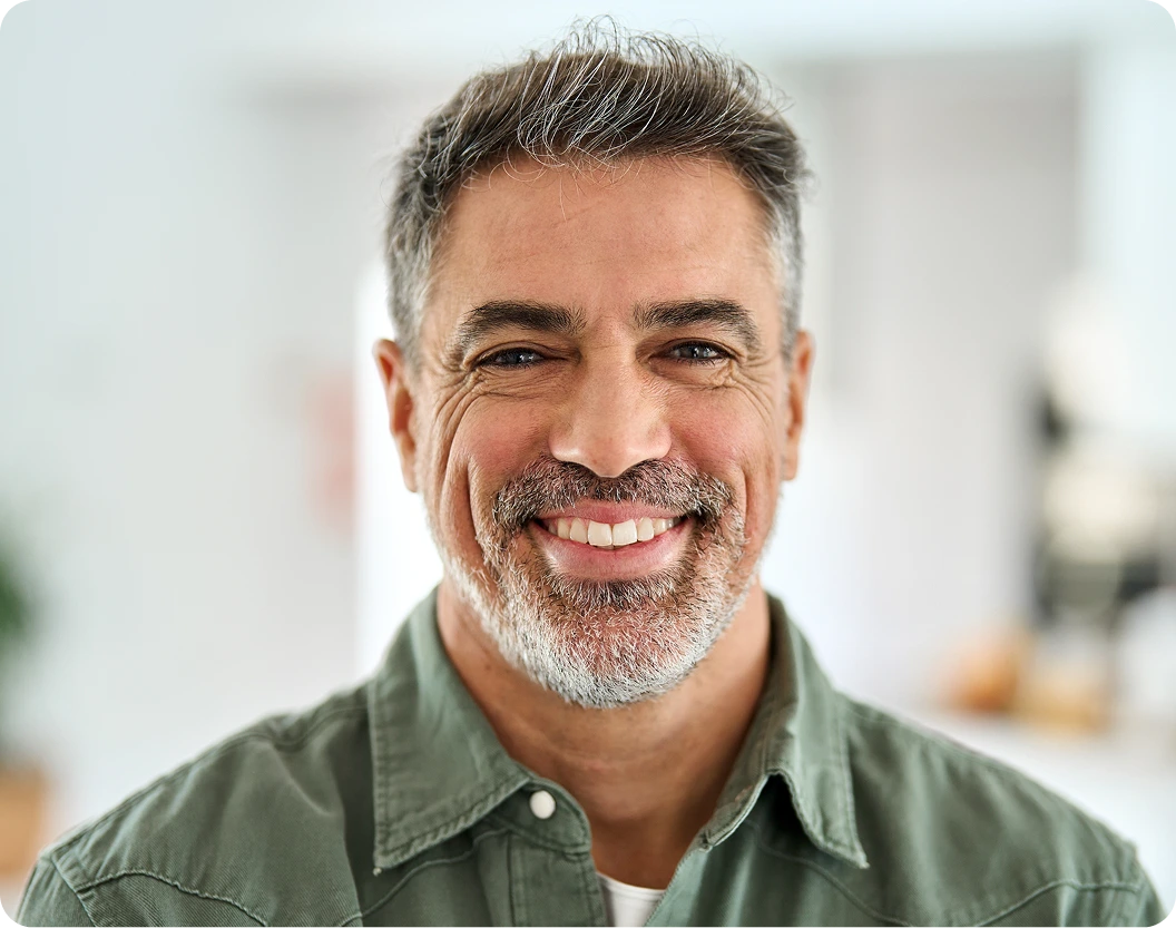 Male dentist smiling in green shirt in modern dental office