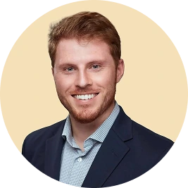 Dr. Kevin Ross headshot - man in blue blazer smiling against cream background