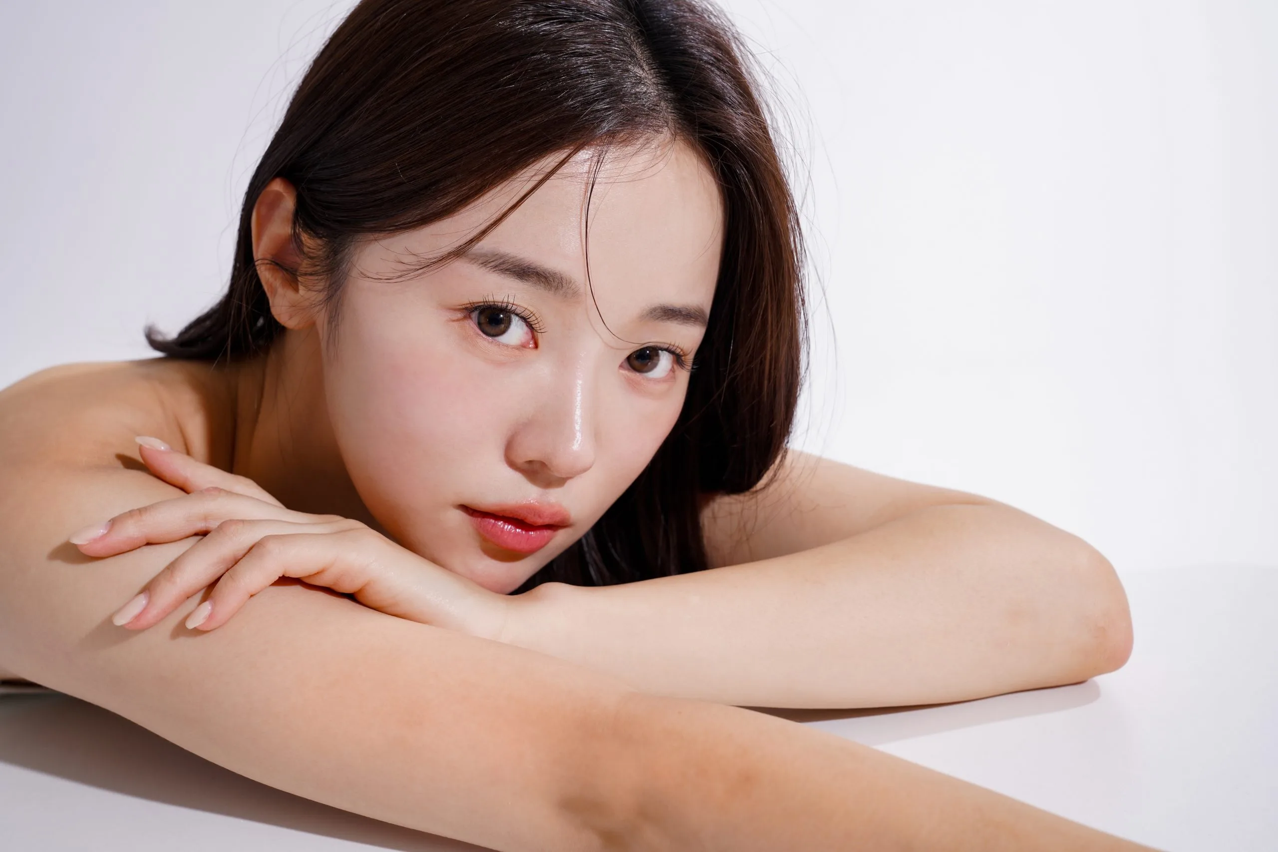 Woman with clear skin smiling and resting her head on her arm