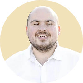 Team member headshot - man in white shirt smiling against cream background